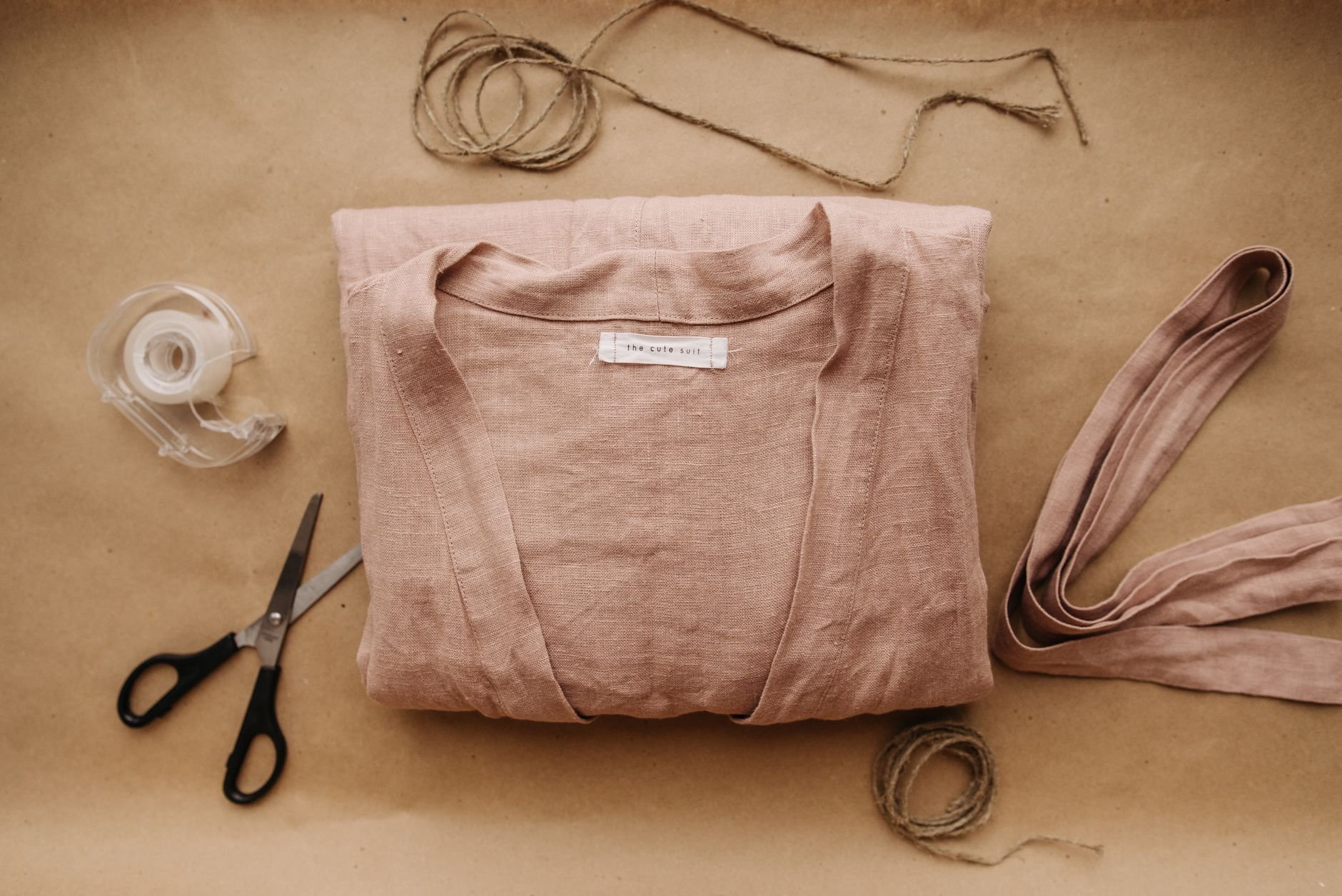 Folded linen clothing alongside packaging materials — the craft of considered apparel